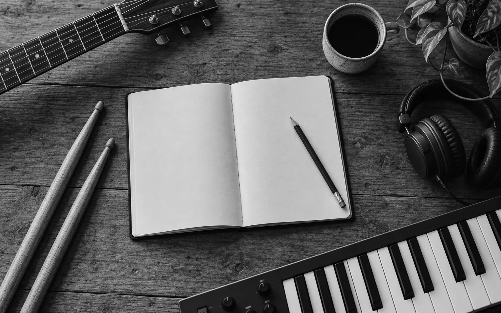 Clavier, manche de guitare et baguettes de batterie autour du carnet vierge d'un auteur-compositeur