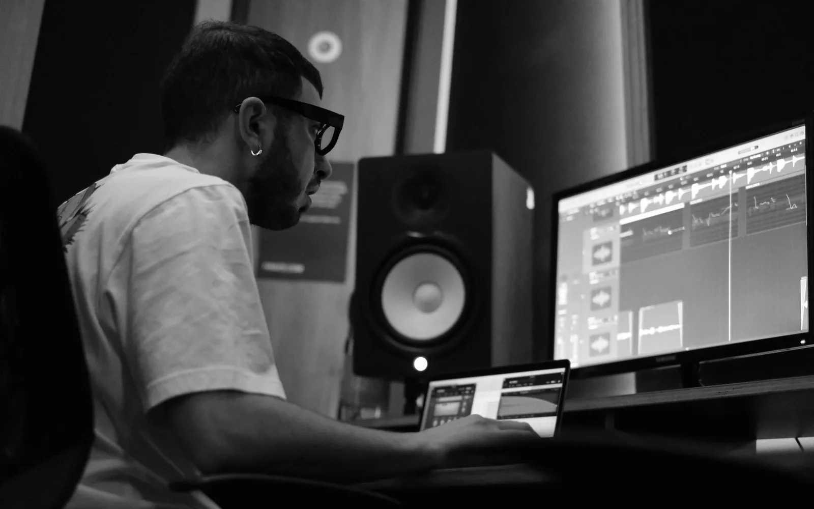 Ein Produzent bearbeitet Audio auf mehreren Bildschirmen in einem Musikstudio