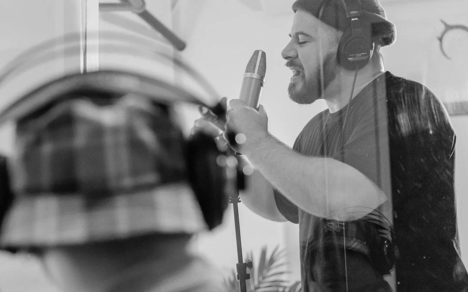 Un chanteur portant un casque enregistrant devant un microphone de studio