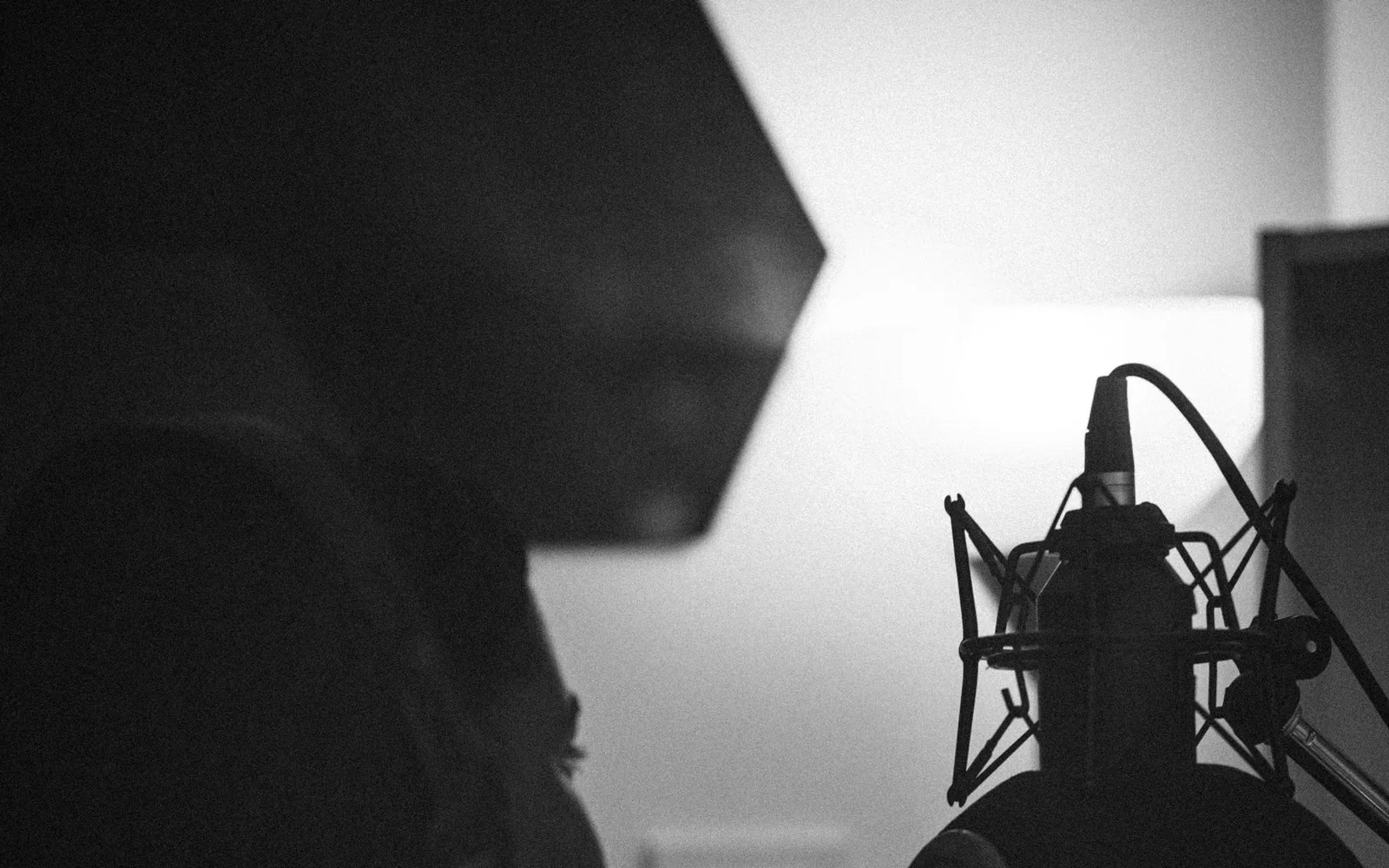 Un chanteur interprétant devant un microphone à condensateur dans une cabine d'enregistrement