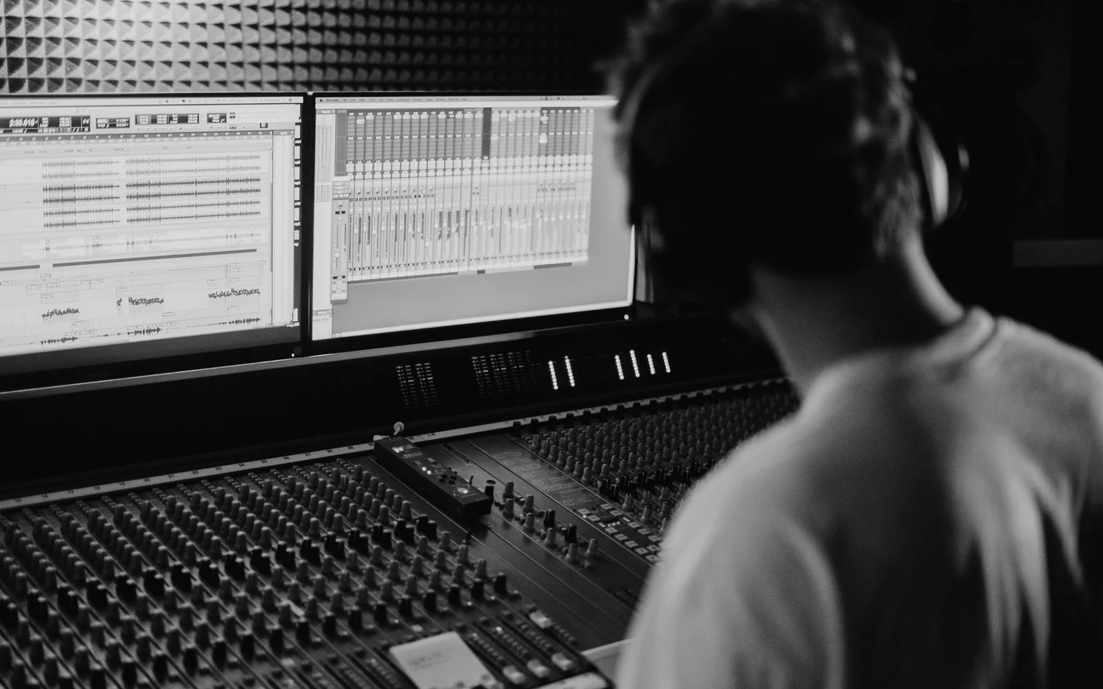 Un técnico de sonido trabajando en una mesa de mezclas de estudio