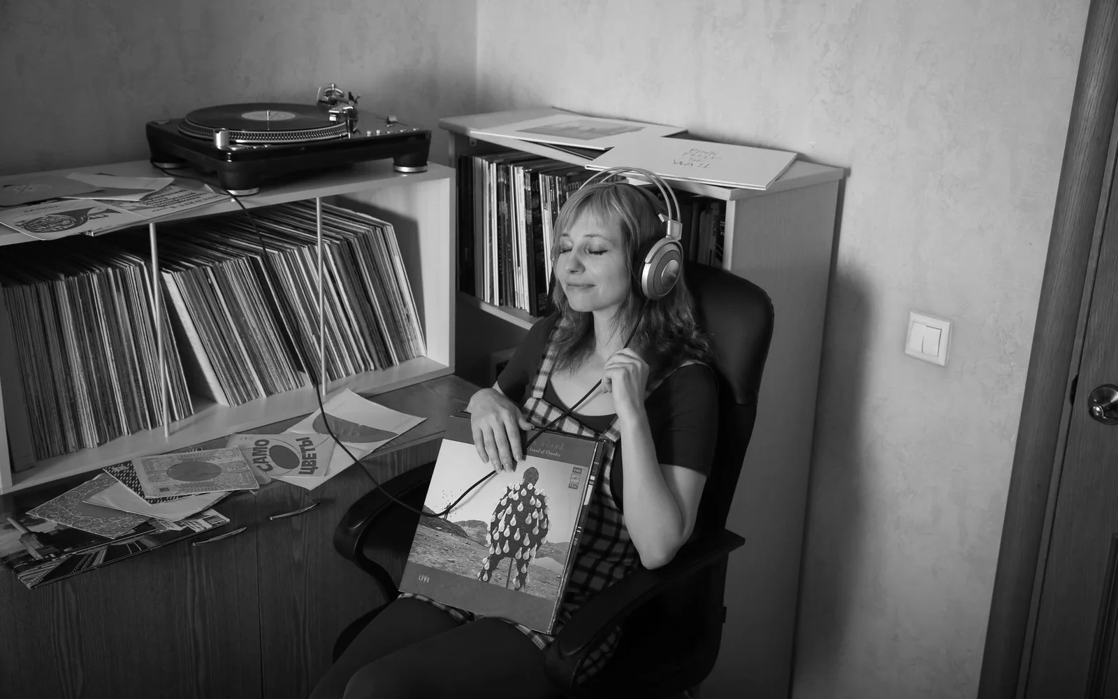 Una mujer escuchando música con auriculares junto a una colección de discos