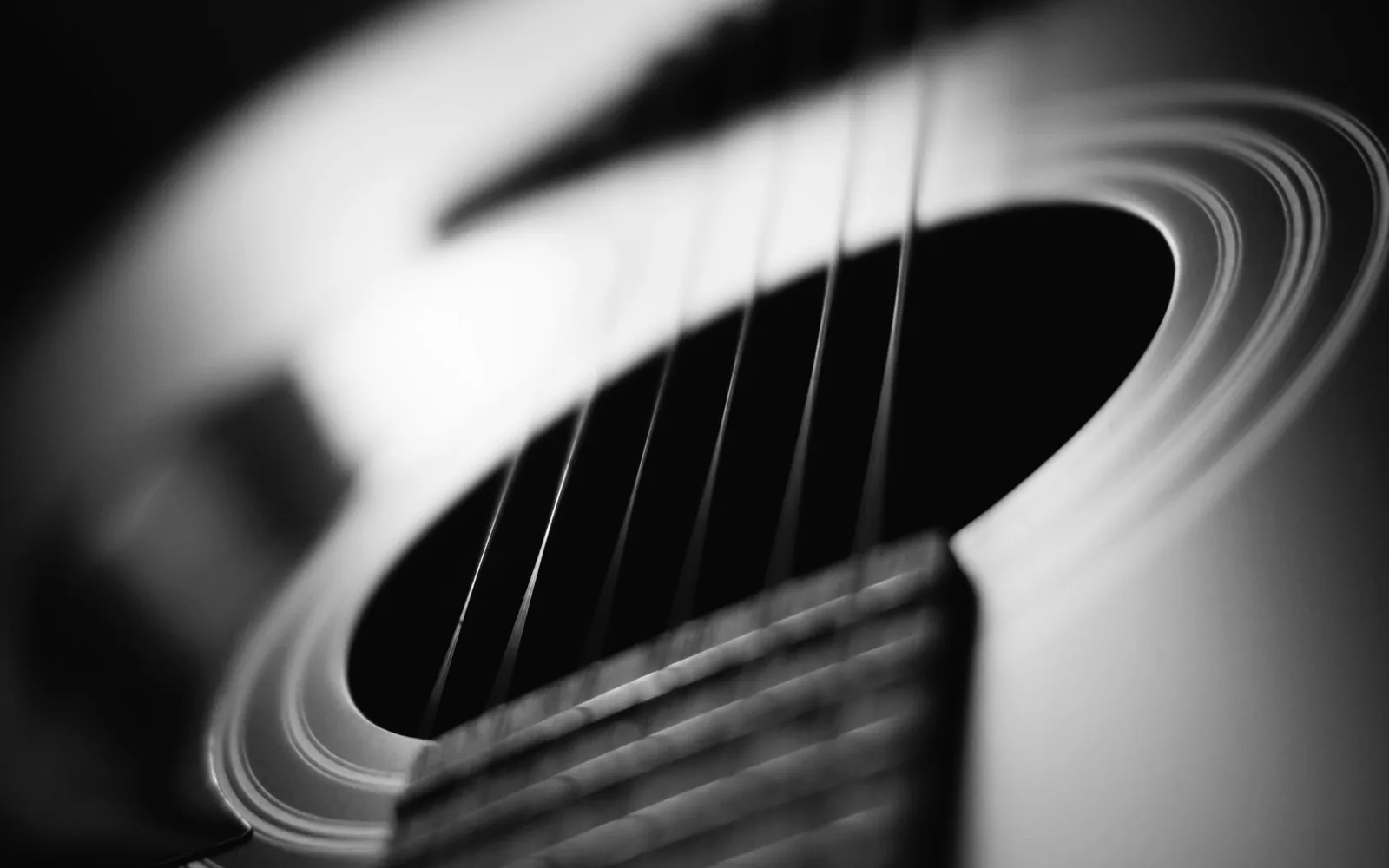 Primo piano dettagliato di una chitarra acustica, che ne evidenzia le corde e le curve con illuminazione drammatica