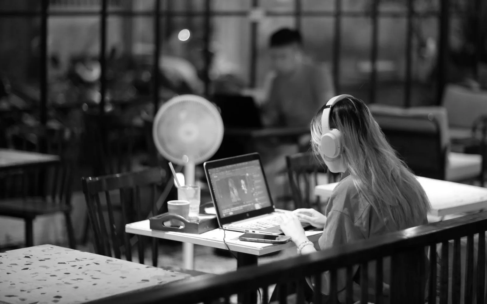 Uma mulher usando fones de ouvido enquanto edita vídeo em um laptop