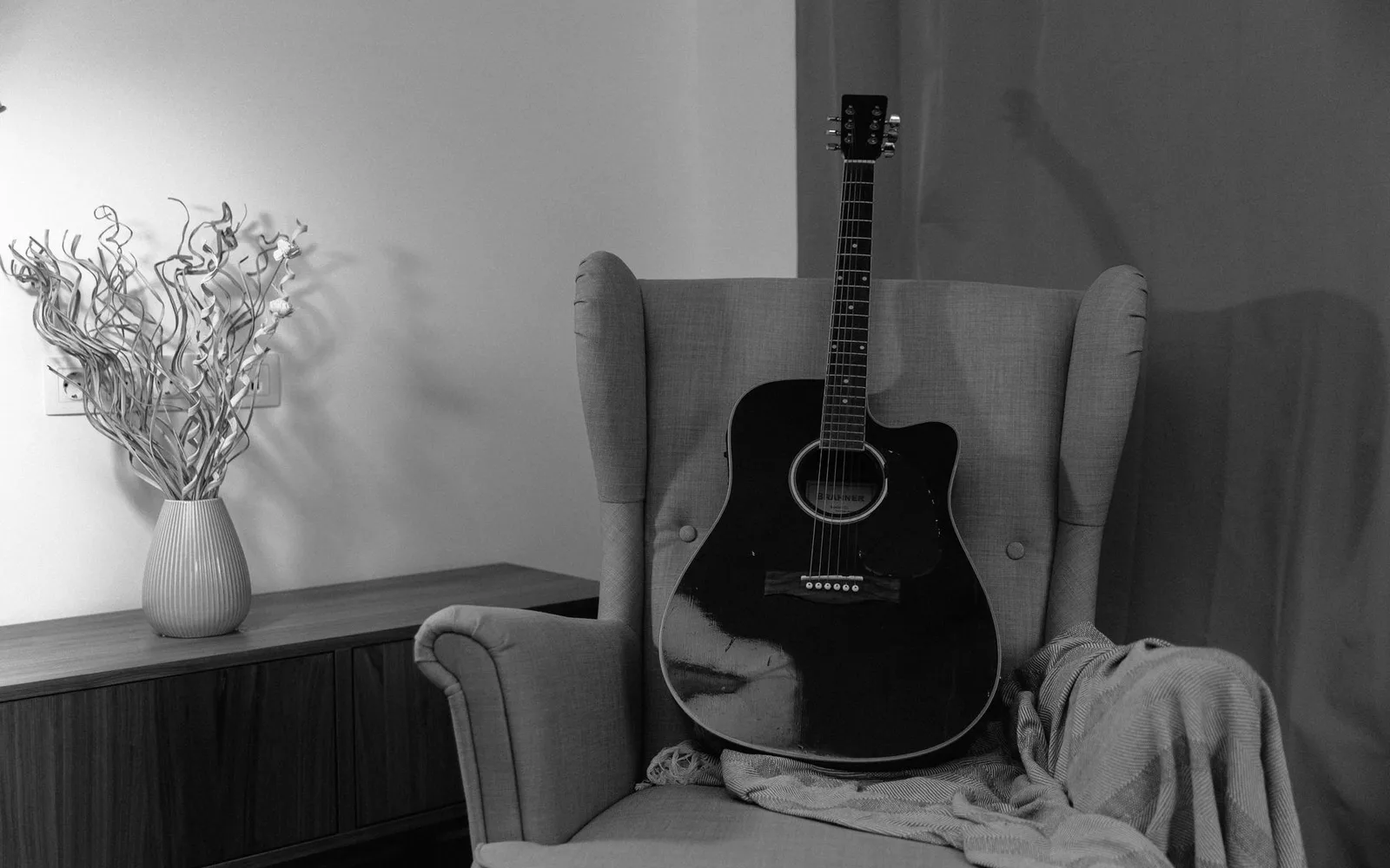Una chitarra acustica appoggiata su una comoda poltrona in un salotto illuminato da luce calda