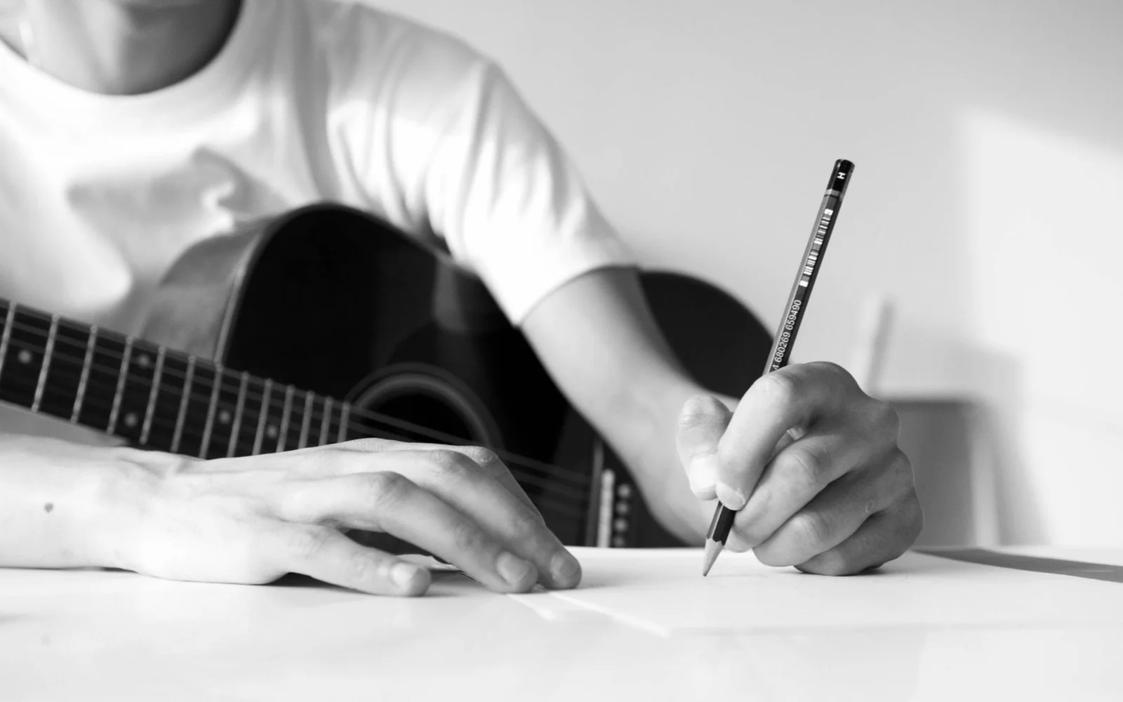 Um guitarrista fazendo anotações ao lado de um violão
