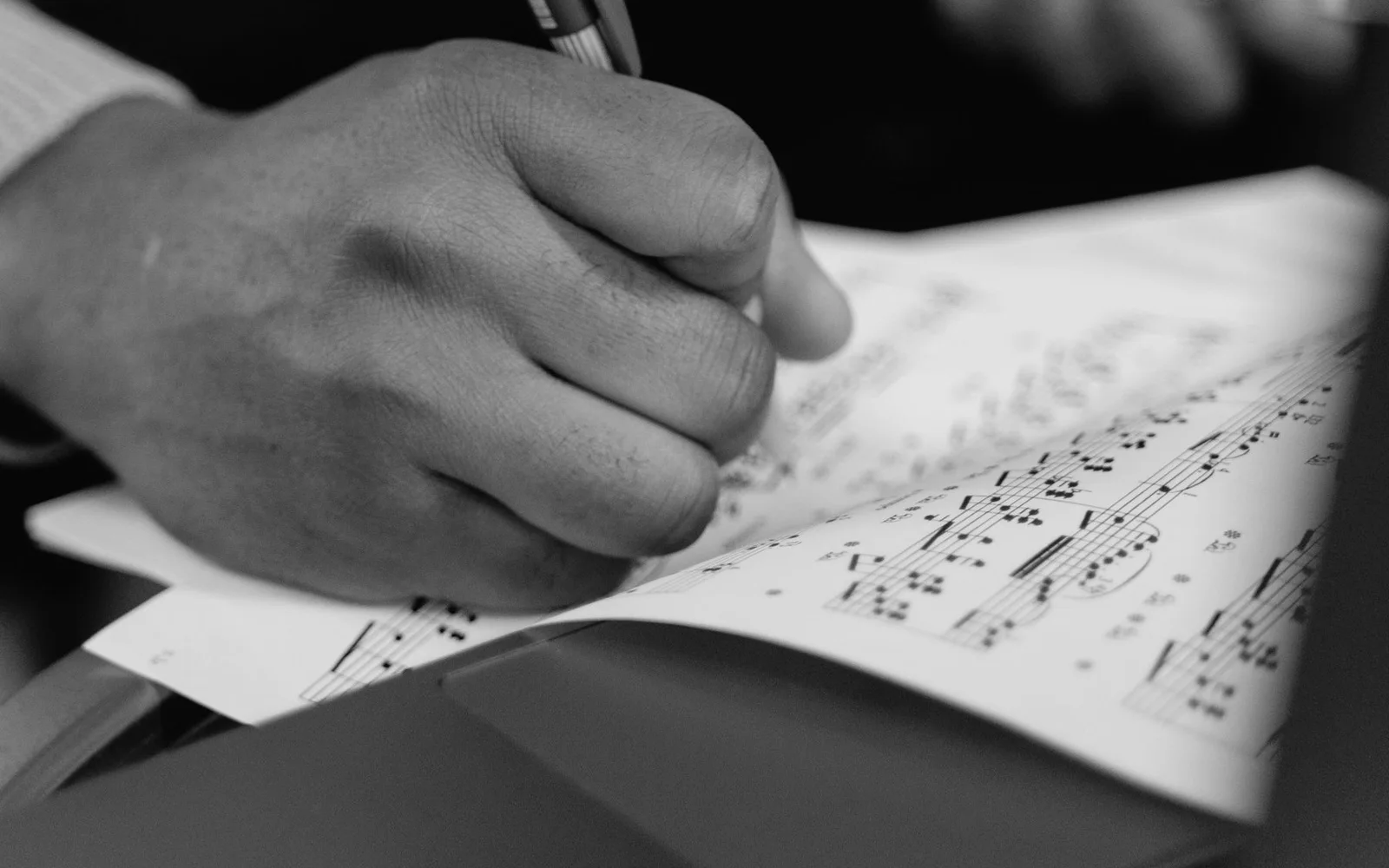 Un musicista che scrive su uno spartito mentre tiene una chitarra