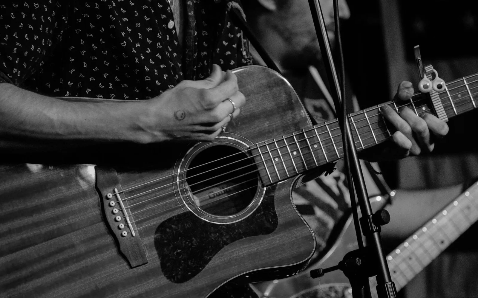 Mani che suonano una chitarra acustica durante un'esibizione musicale dal vivo a Boston
