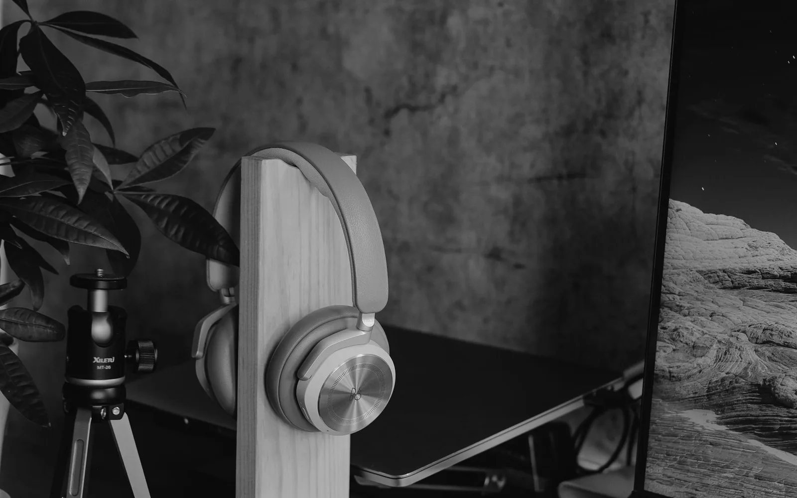 Spazio di lavoro contemporaneo con cuffie su un supporto in legno, monitor del computer e accessori