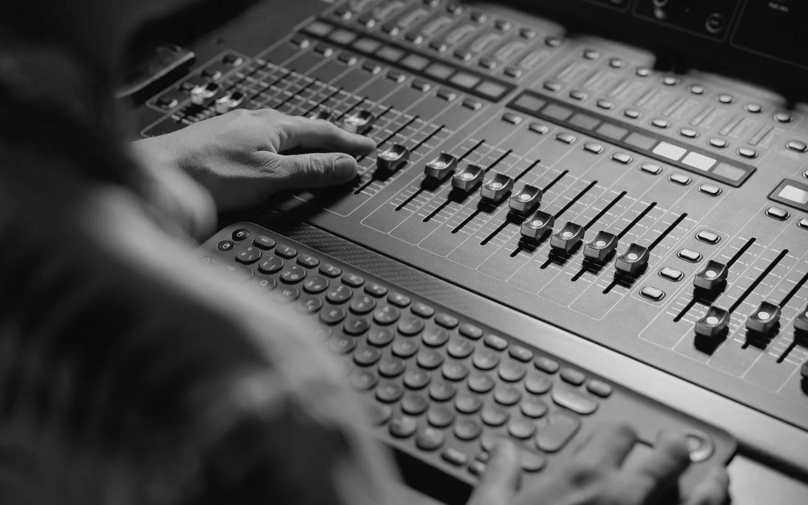 Un tecnico del suono che regola un mixer audio da studio