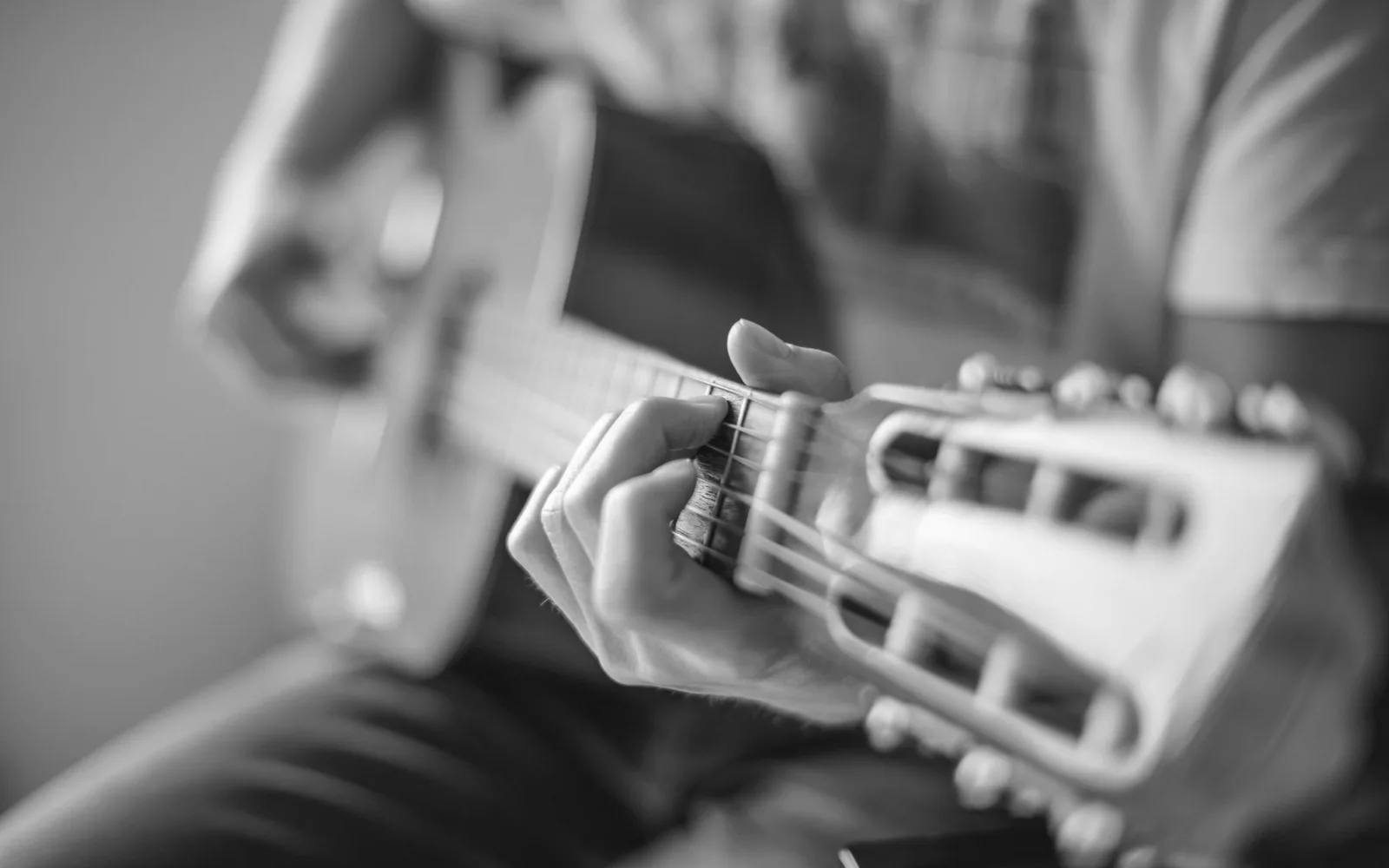 Una persona che suona una chitarra acustica, concentrandosi sul posizionamento della mano sulla tastiera