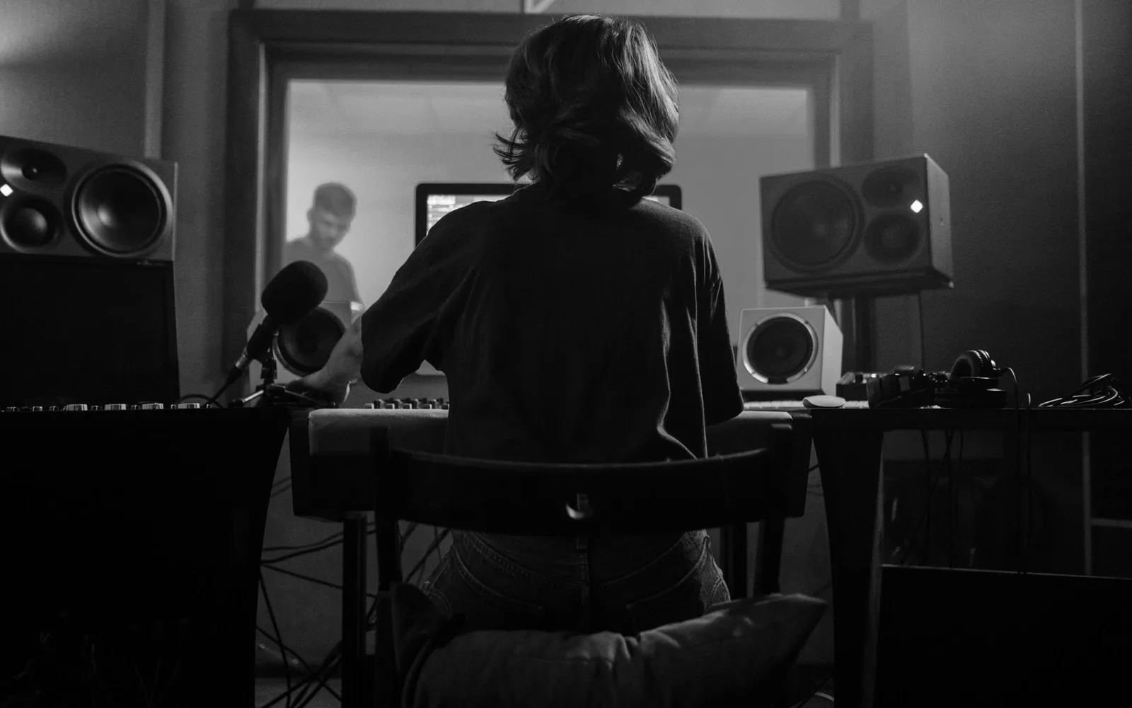 Un produttore musicale lavora in uno studio di registrazione con microfoni e altoparlanti, creando contenuti audio