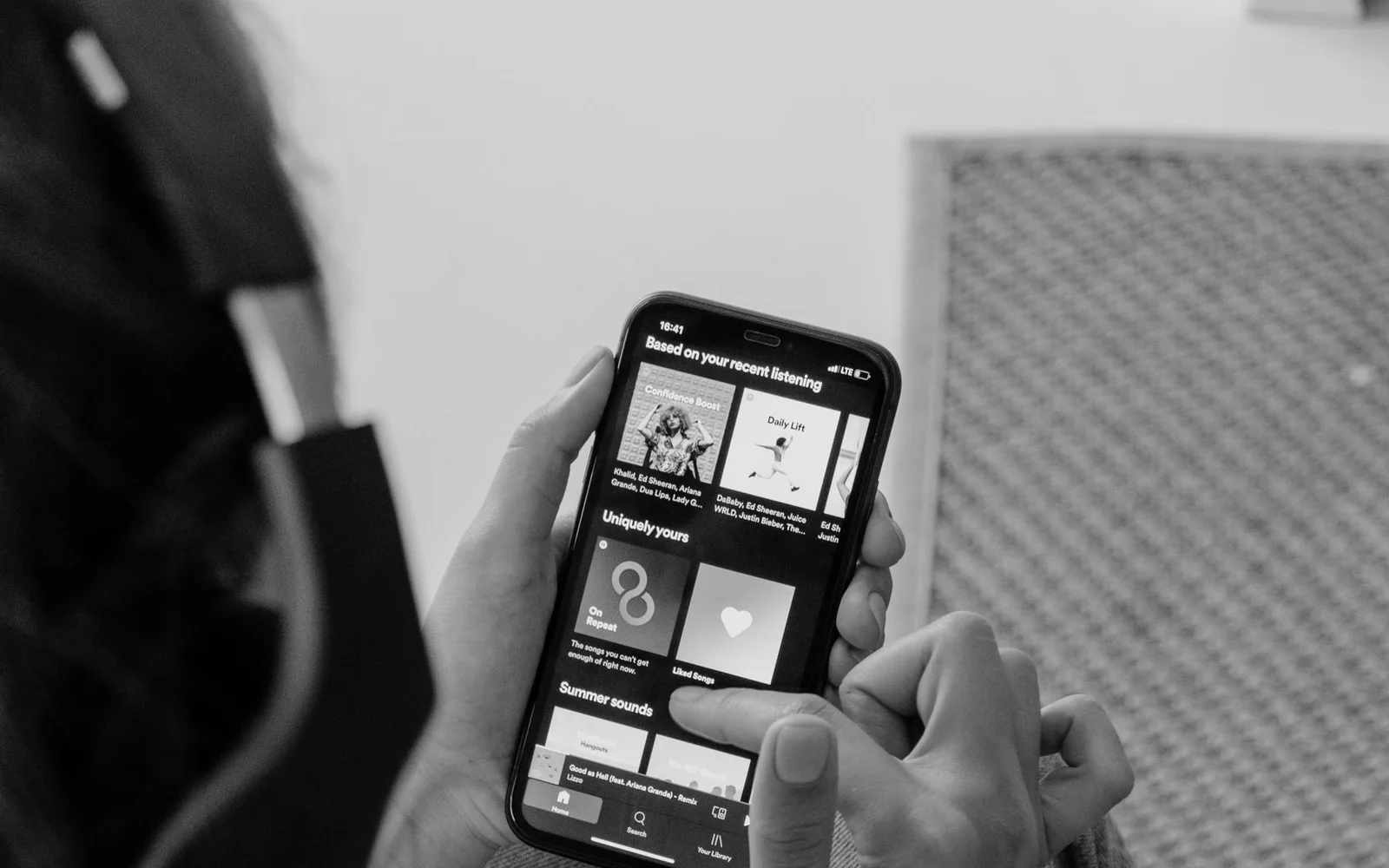 Um ouvinte usando um smartphone e fones de ouvido em ambiente interno