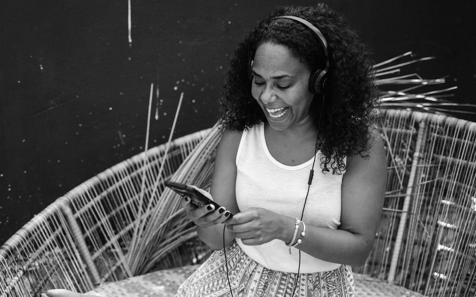 Uma mulher ouvindo com fones de ouvido enquanto verifica o telefone ao ar livre