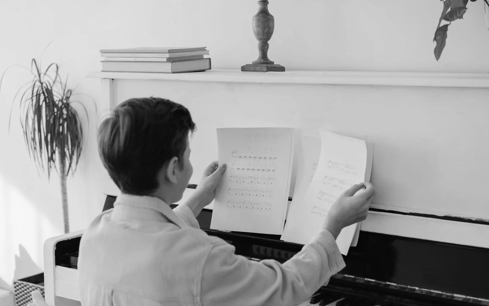 Ragazzo seduto al pianoforte con spartiti, che illustra l'apprendimento e lo sviluppo delle abilità al chiuso