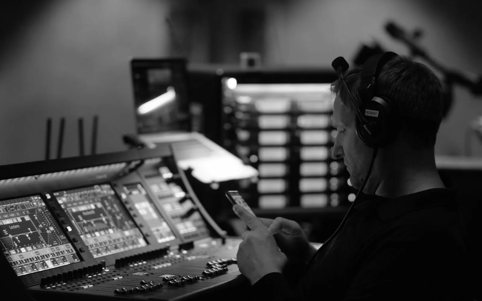 Un ingegnere del suono in uno studio, concentrato sull'attrezzatura audio e uno smartphone