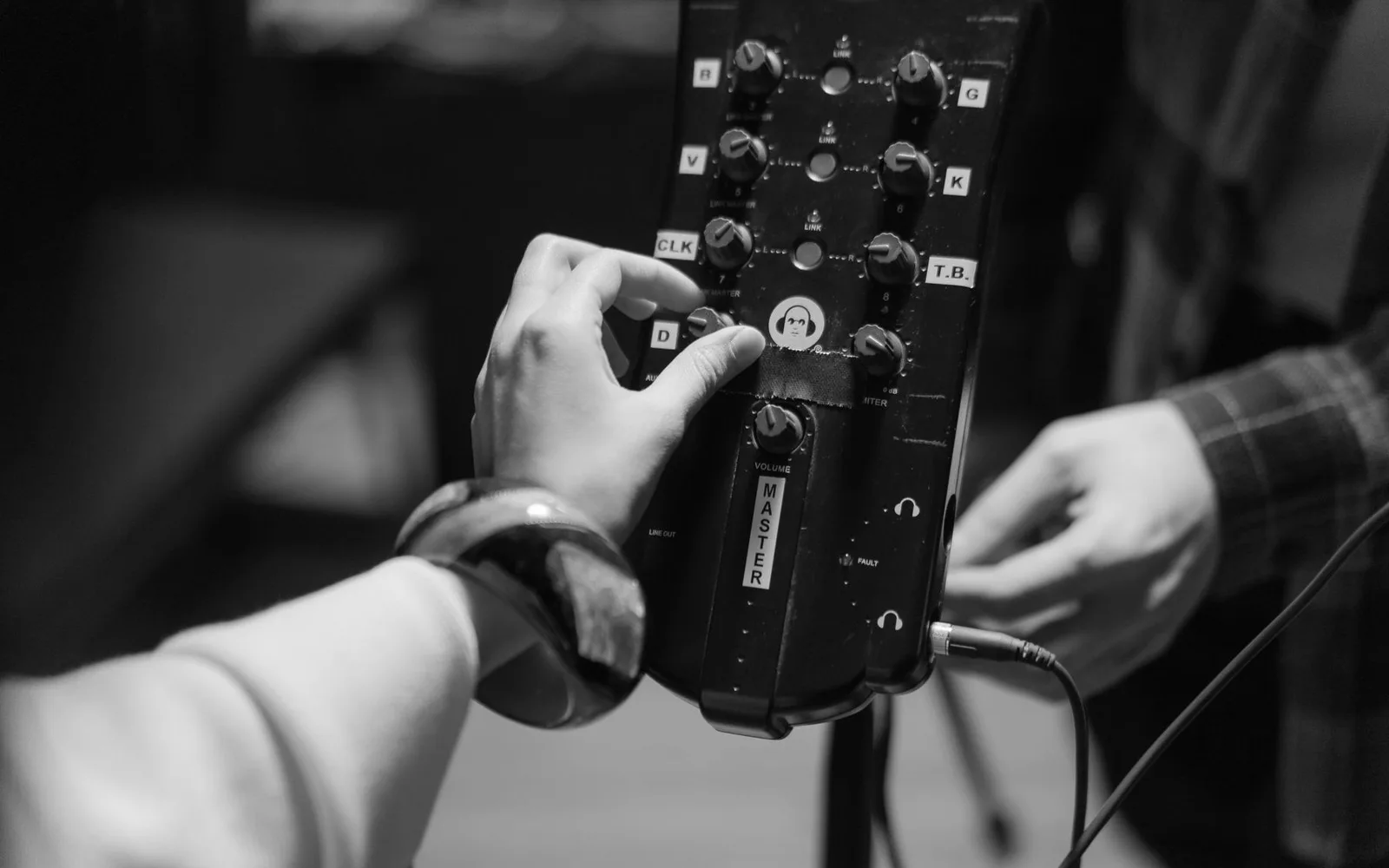 Primo piano di mani che regolano i controlli di un dispositivo audio per la produzione e la registrazione musicale