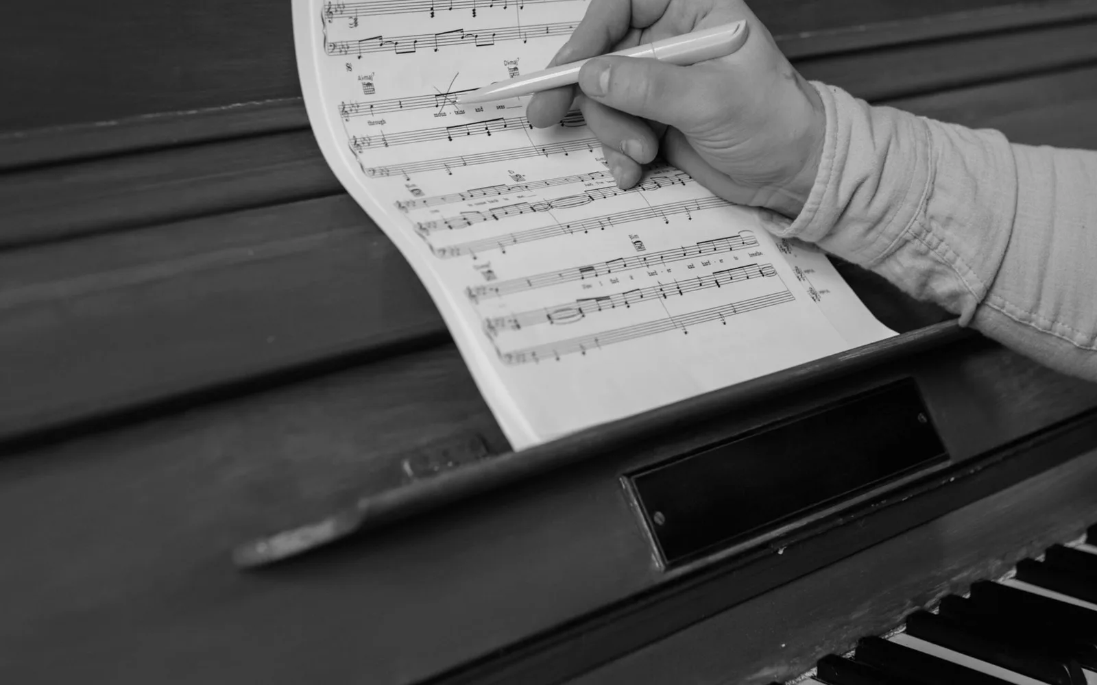 Primo piano di un compositore che rivede uno spartito su un pianoforte rosso
