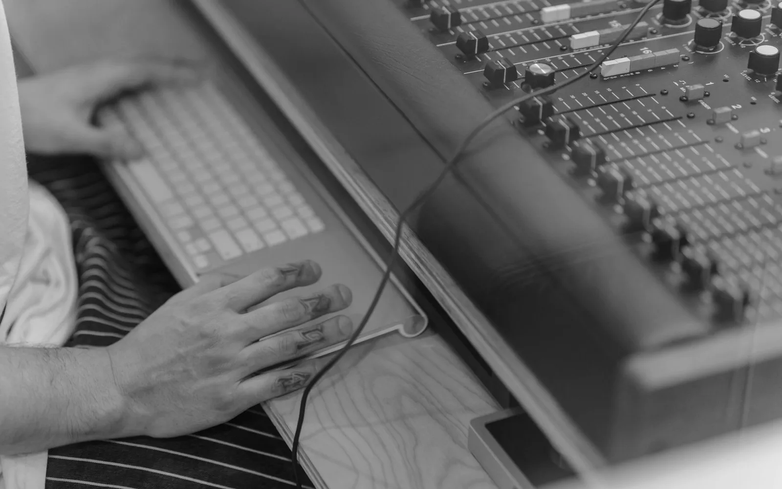 Un musicien travaillant à une table de mixage avec une guitare posée sur ses genoux