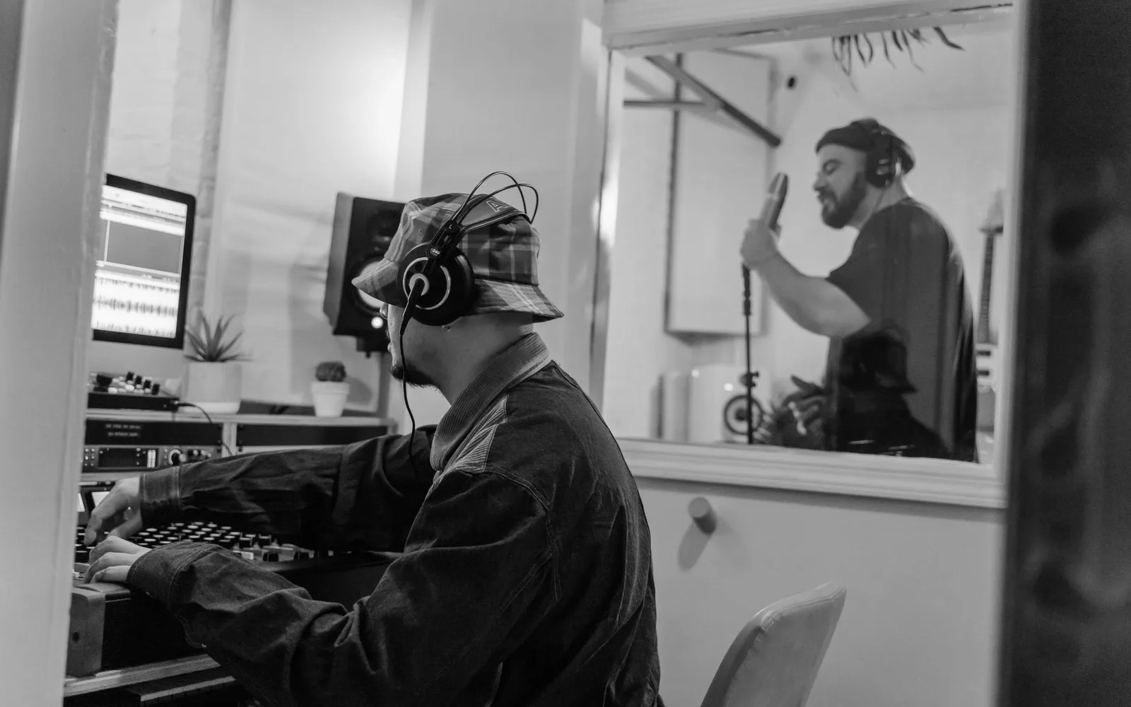 Ein Sänger und Produzent arbeiten in einem Studio an einer Aufnahme
