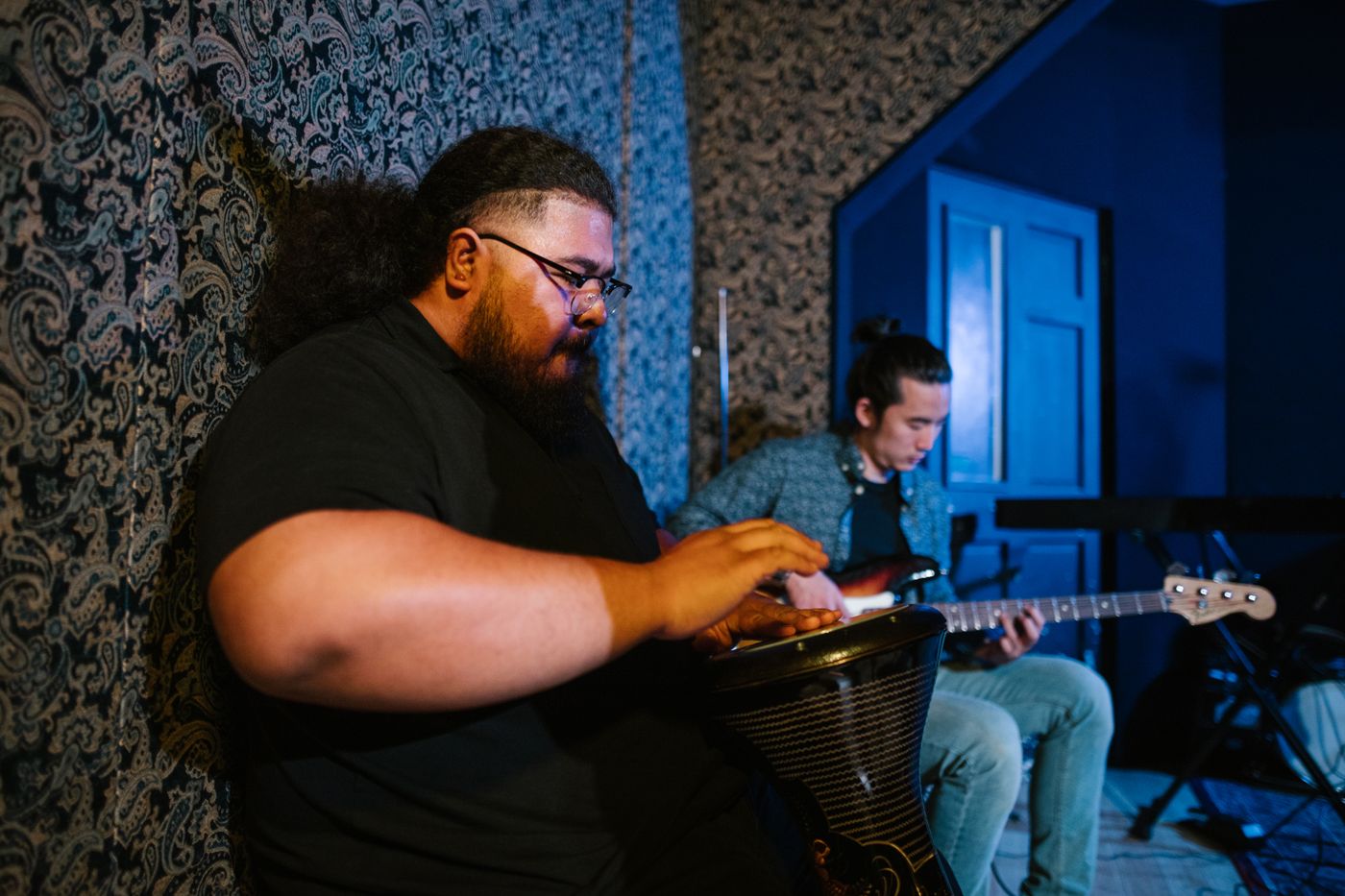 Zwei Musiker spielen Gitarre und Handtrommel in einem Proberaum
