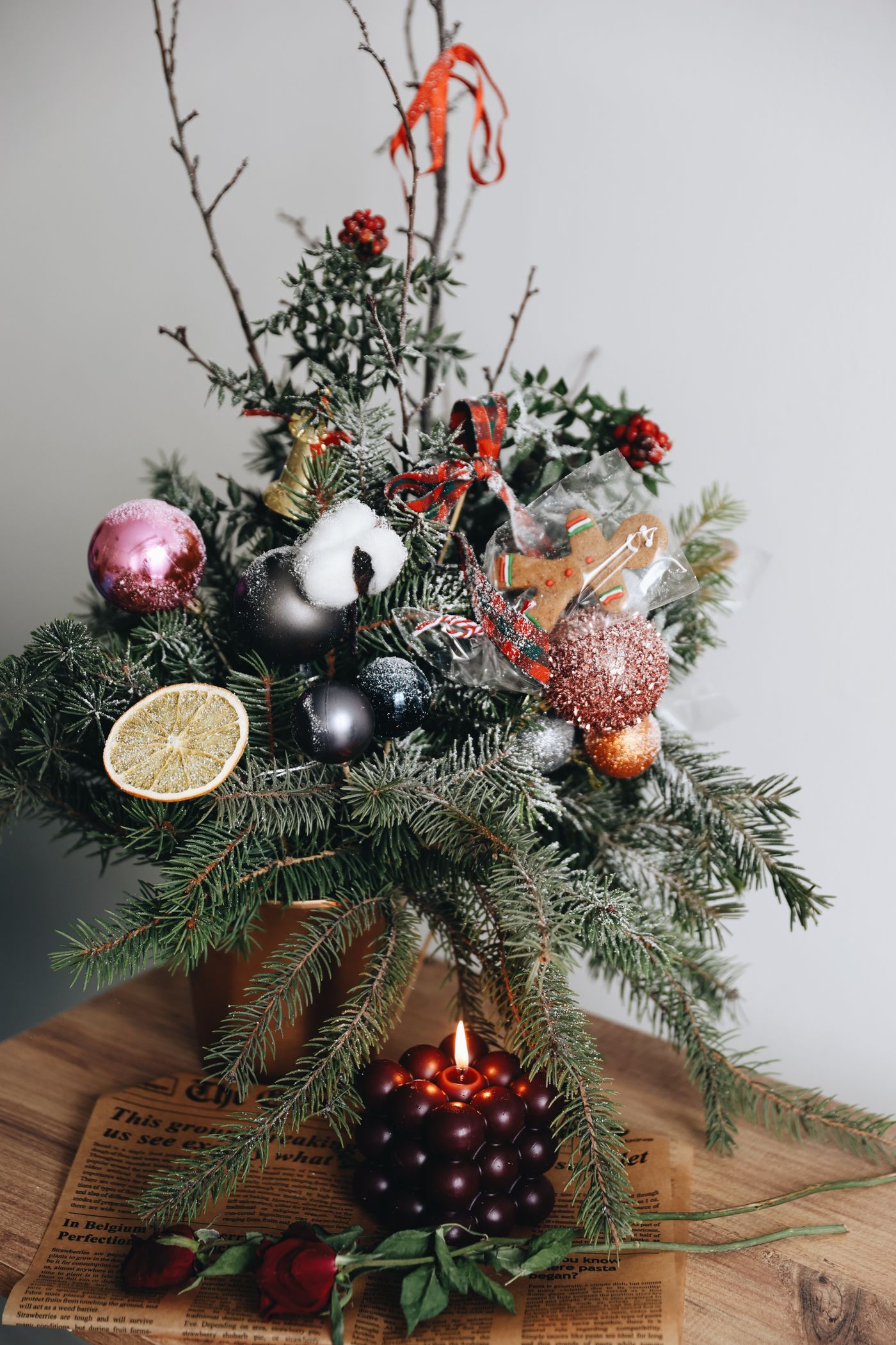 Eine Kerze umgeben von Weihnachtszweigen und Ornamenten