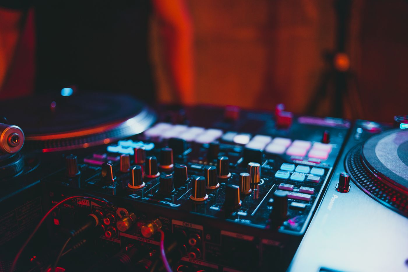 Close view of a DJ mixer with illuminated controls in a dark venue