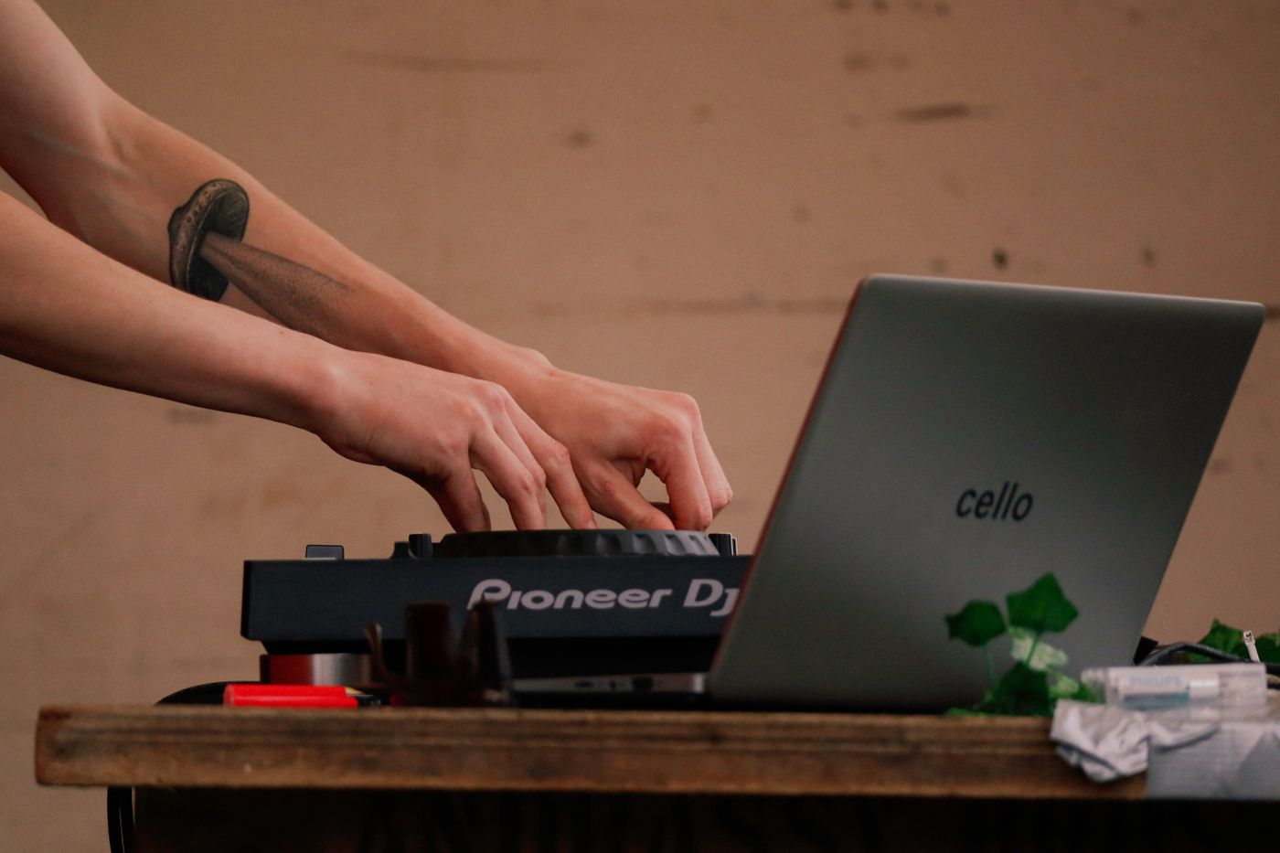 Hands adjusting a DJ controller beside a laptop on a performance desk