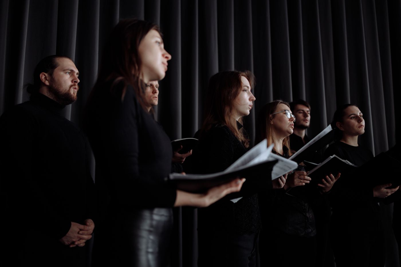 Chormitglieder singen gemeinsam mit Notenblättern in einem Raum