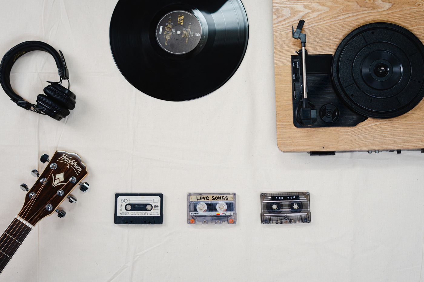 Eine flache Anordnung von Vinyl, Kassetten, Kopfhörern und einer Gitarre
