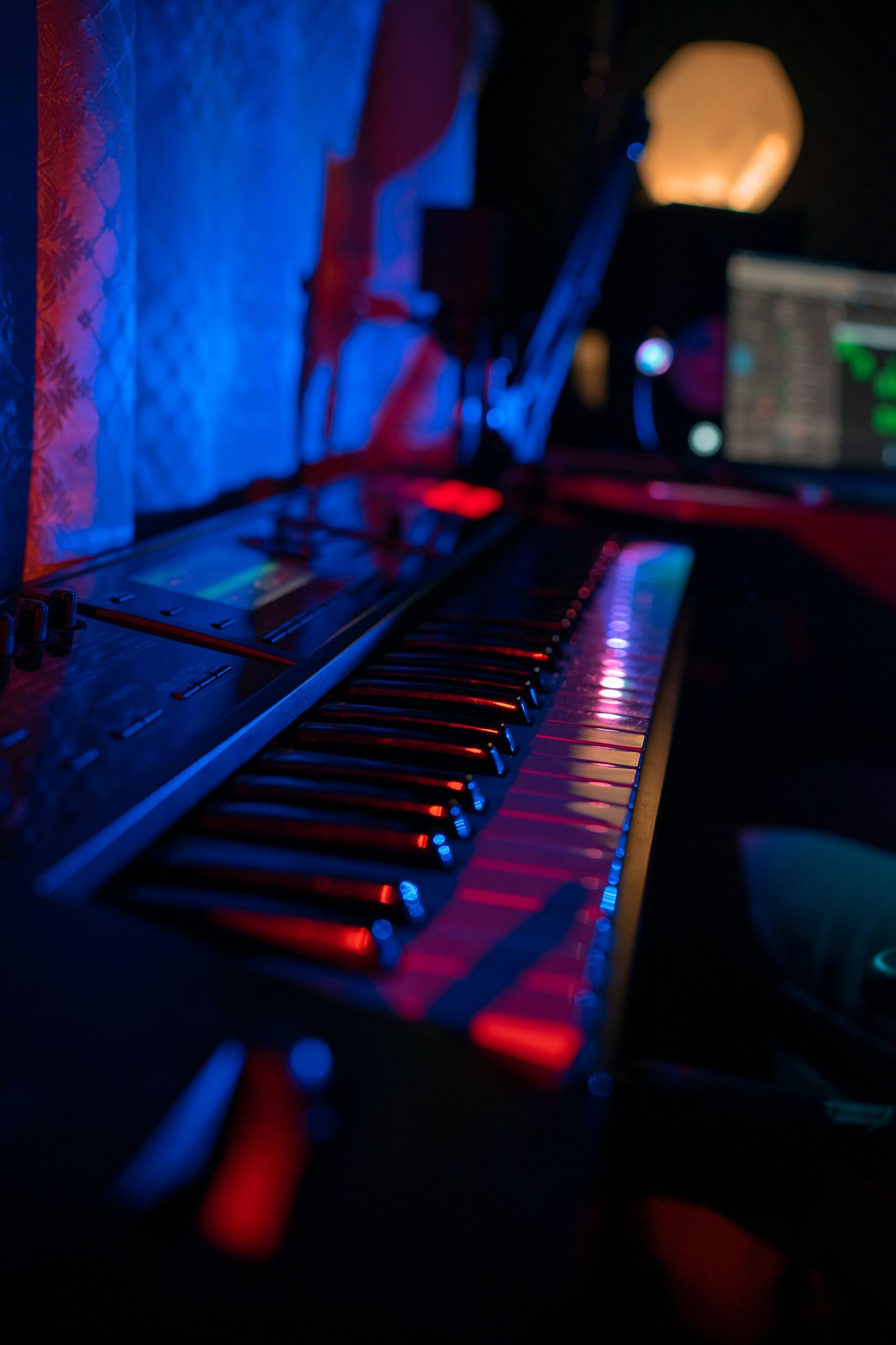 Synthesizer keyboard and computer in a dimly lit music studio