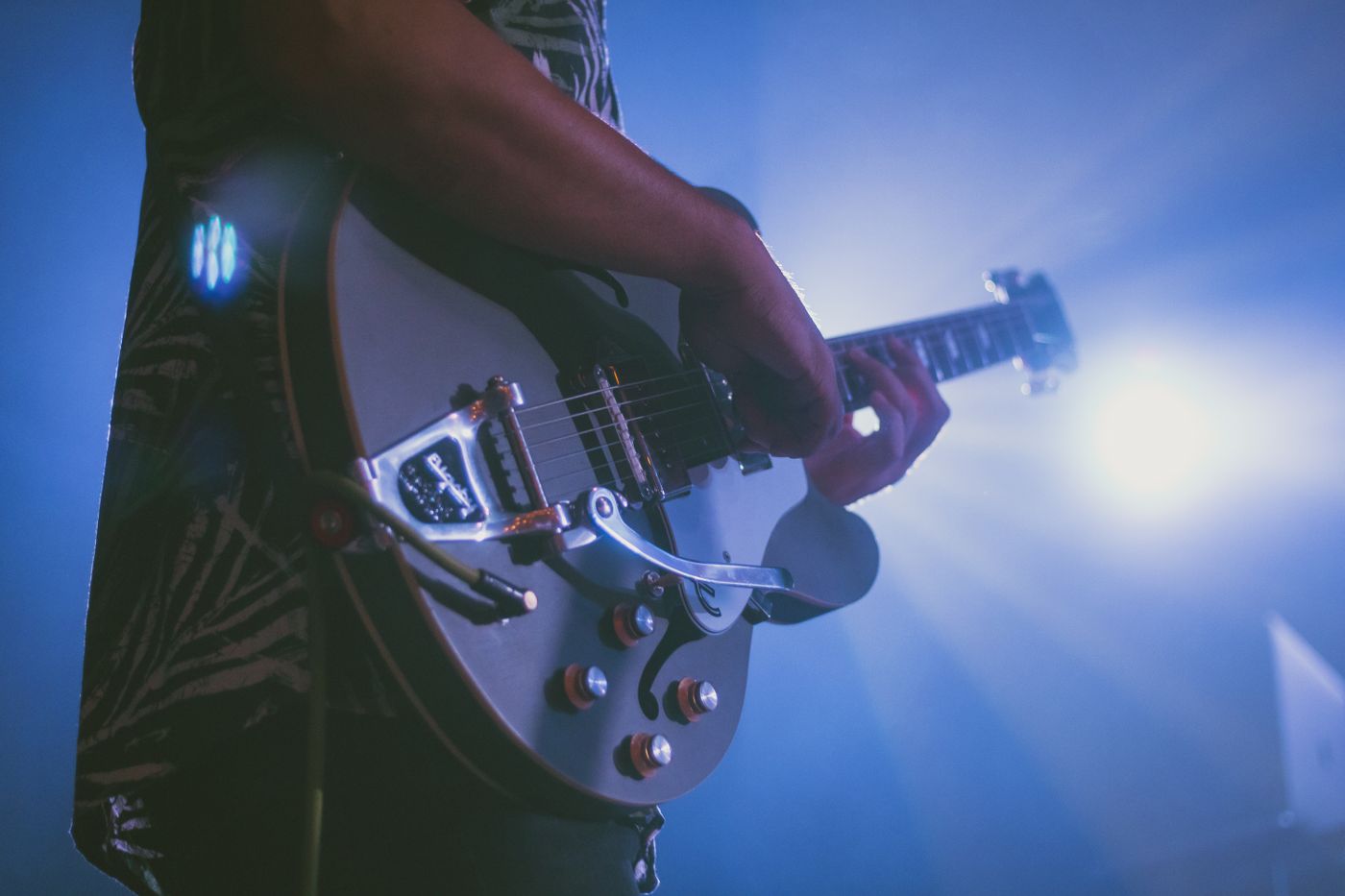 Close view of a musician playing electric guitar under stage lights