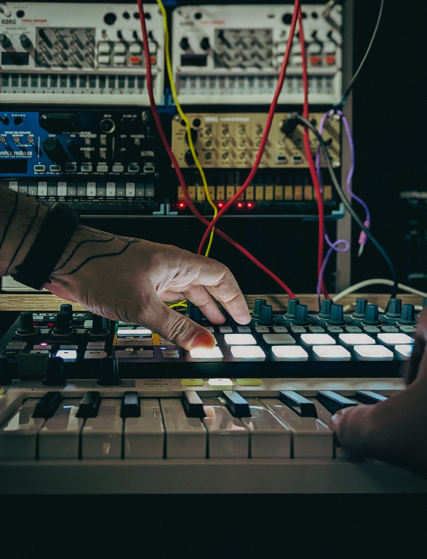 Hände, die Tastatur- und Produktionssteuerungen in einem Studio bedienen