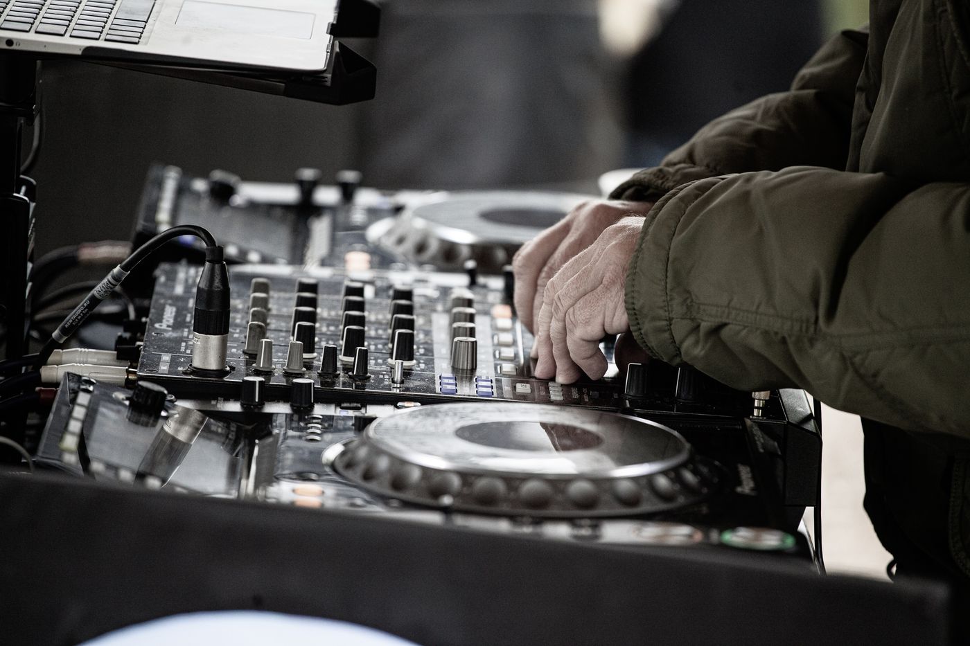 Hände, die einen professionellen DJ-Controller im Freien einstellen
