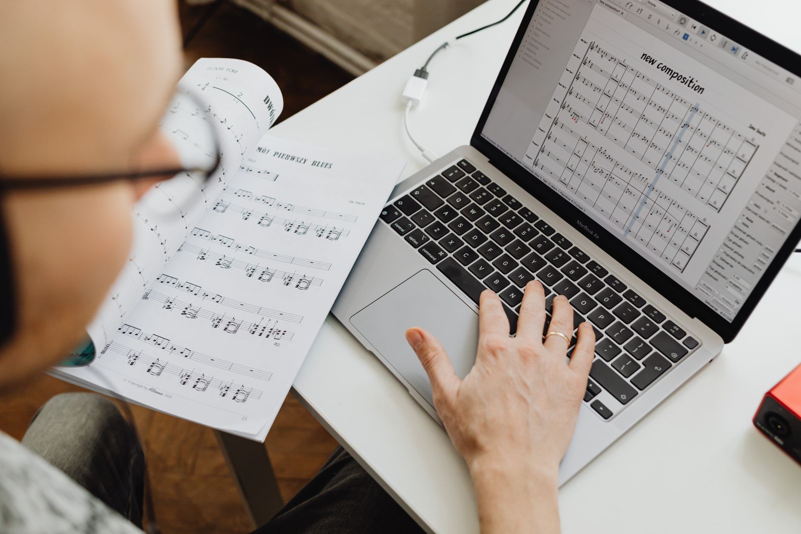 Ein Songwriter arbeitet mit Notenblättern neben einem Laptop