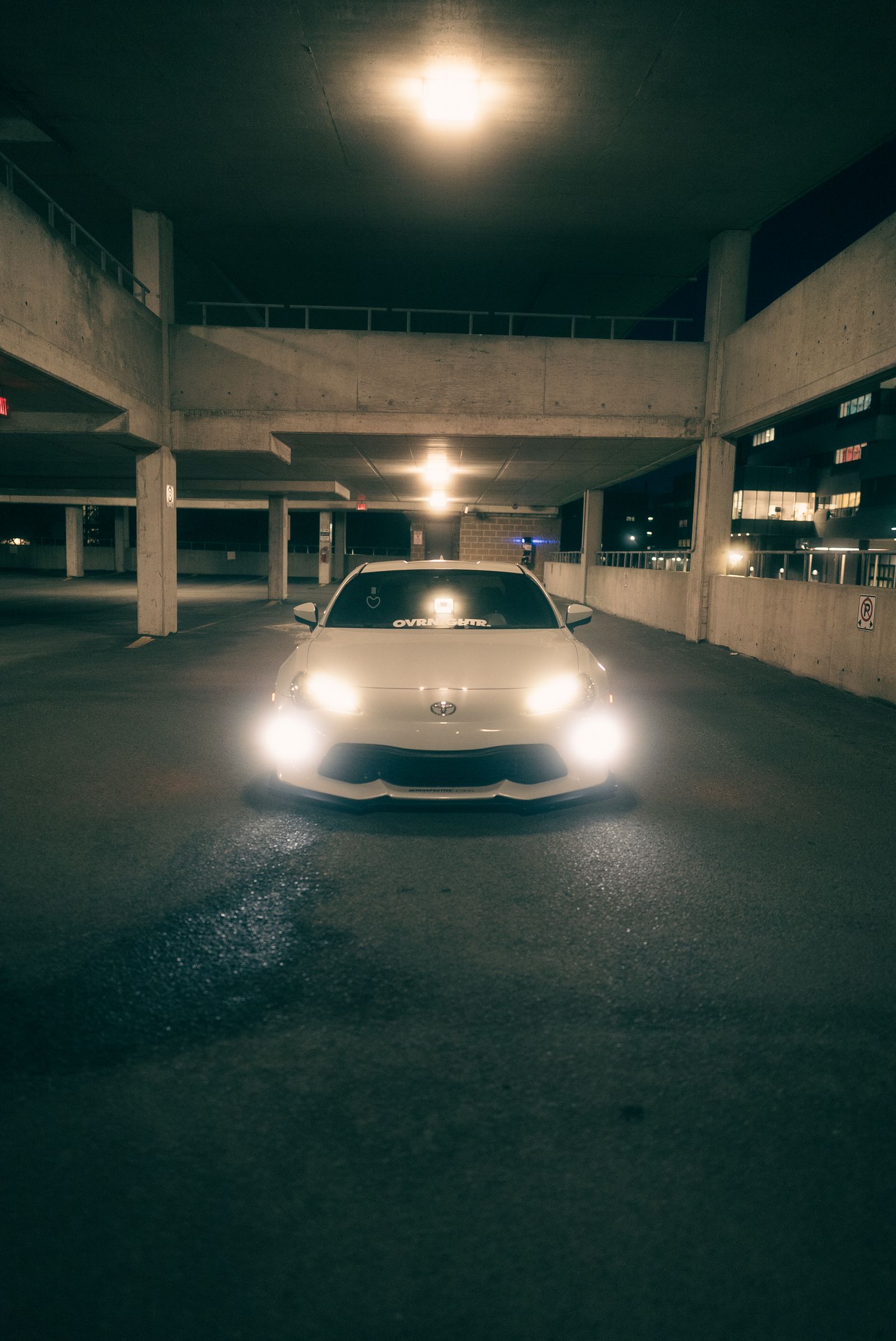 Ein Auto, das nachts unter Deckenleuchten in einer Betonparkgarage geparkt ist