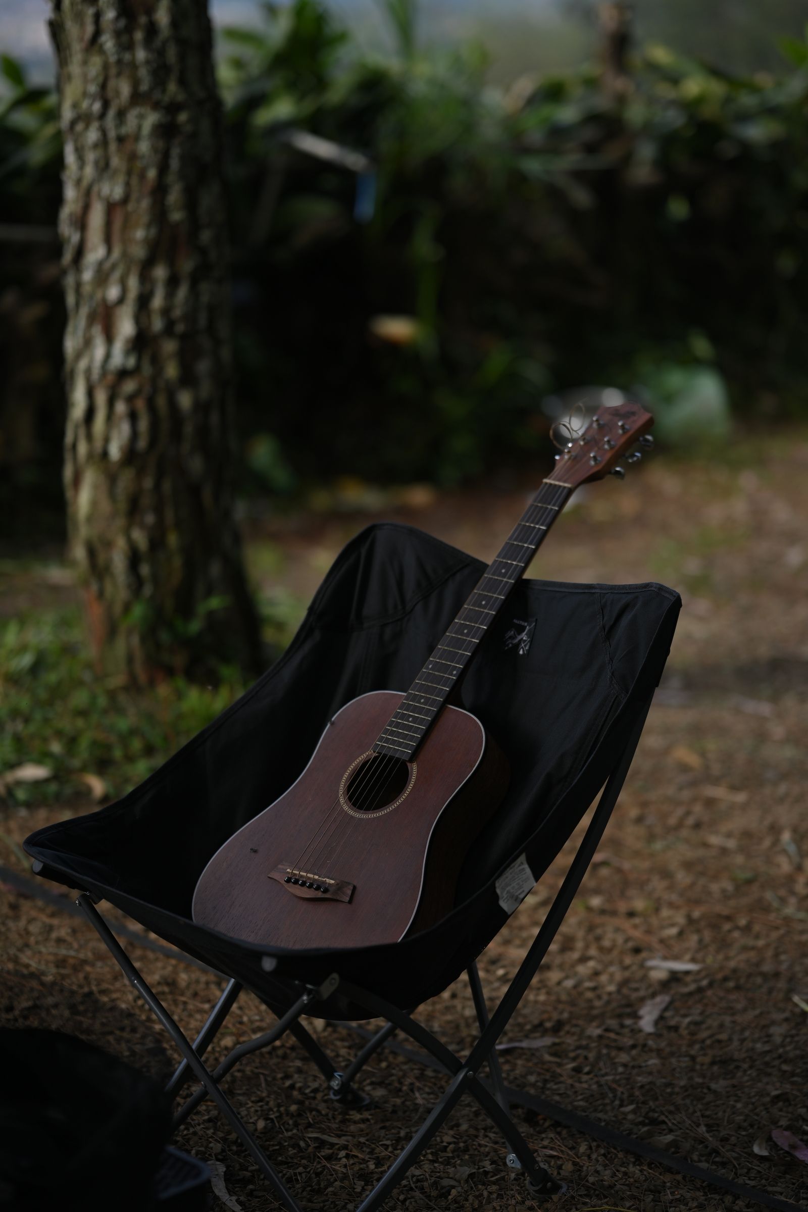 Una guitarra acústica apoyada en una silla al aire libre