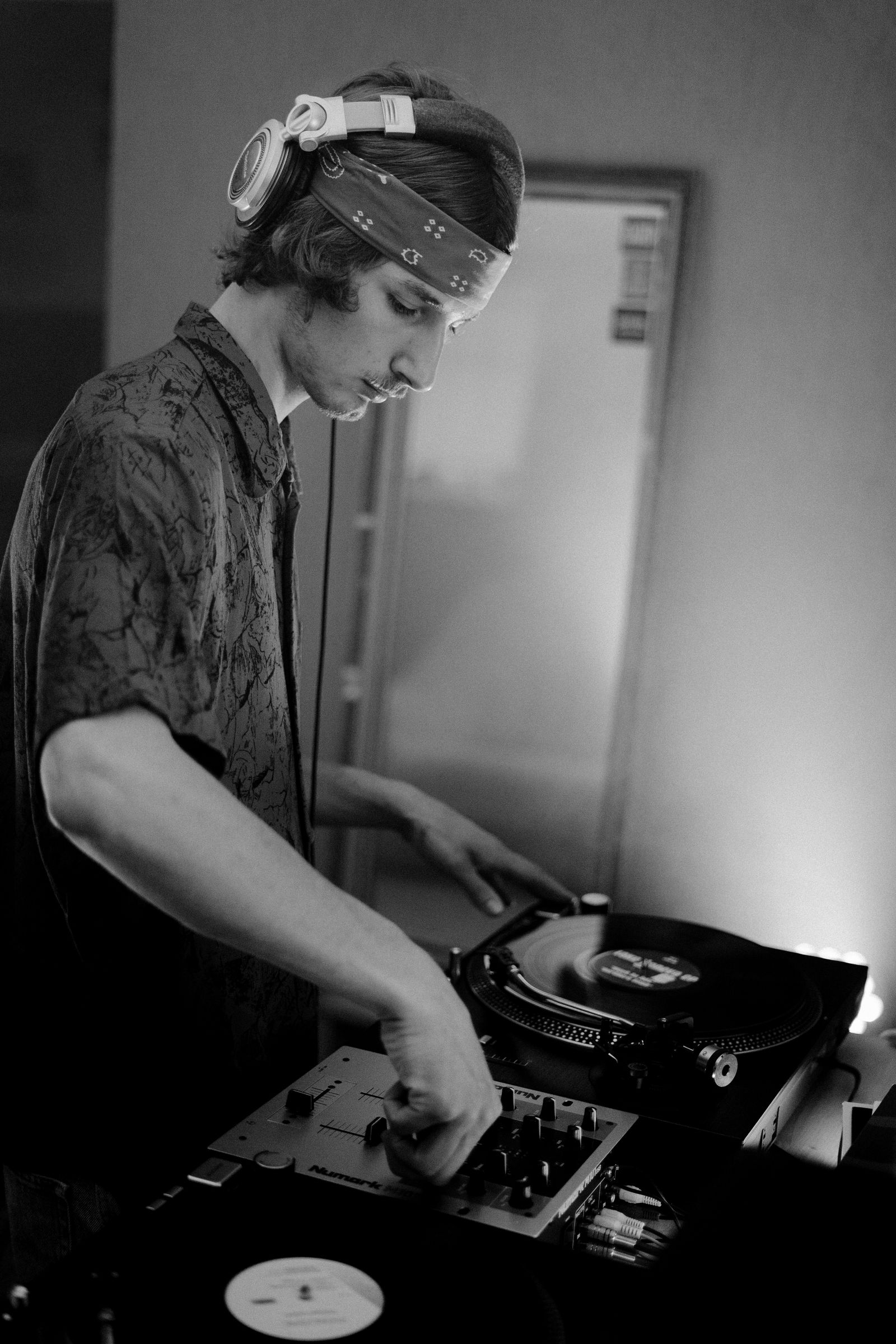 A DJ mixing vinyl records while wearing headphones