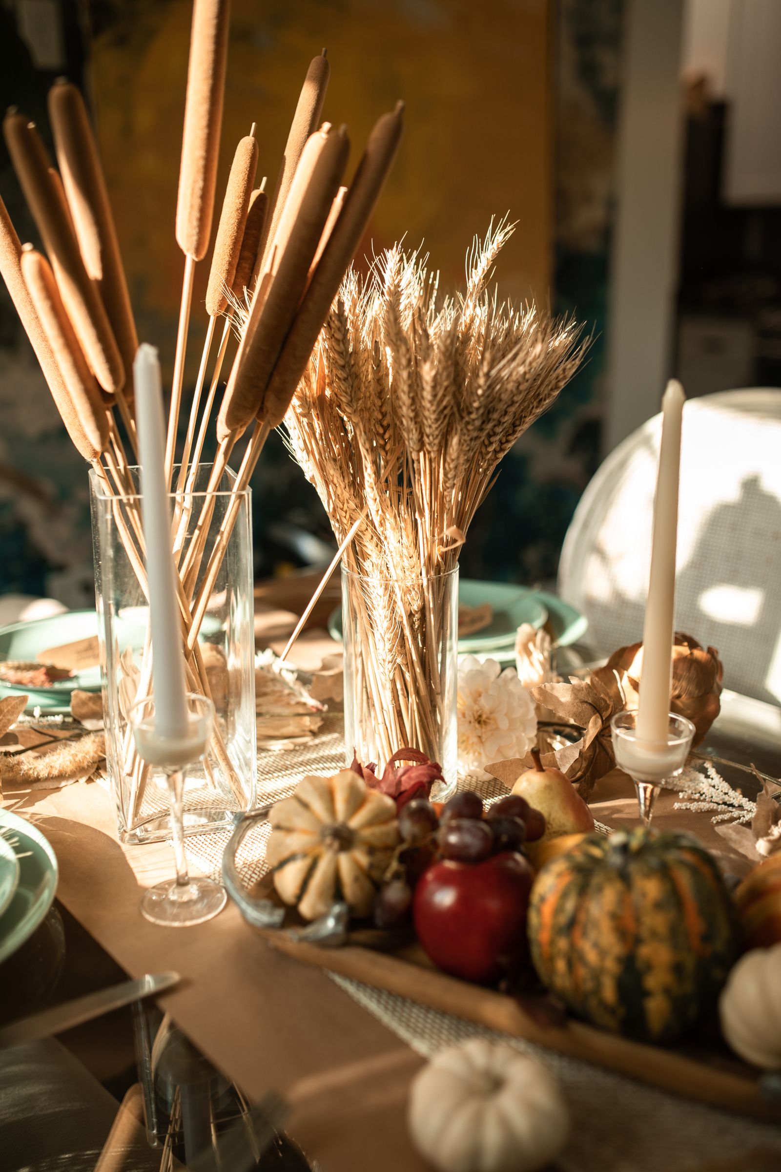An autumn table set with candles, gourds and wheat for a shared meal